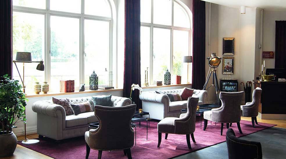Lobby oversigt med lænestole og sofaer ved vindue hos Clarion Collection Hotel Bolinder Munktell Eskilstuna 
