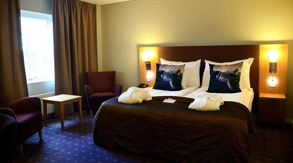 Oversigt superior værelse med stole, badekåber og seng hos Clarion Collection Hotel Kompaniet Nyköping
