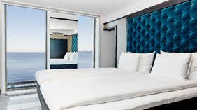 Vox Hotels store hjørnesuite med dobbeltseng i soveværelset og smuk udsigt over Vättern