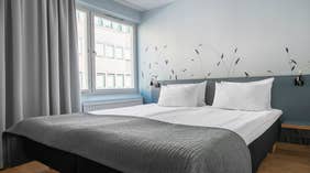 Moderne Standard dobbeltværelse med dobbeltseng, gråt sengetæppe, grå gardiner og motiv på væggen hos Quality Hotel Grand Kristianstad 