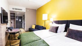 Superior dobbeltværelse med dobbeltseng, sofa, gul væg og siddeområde på Quality Hotel Winn Haninge